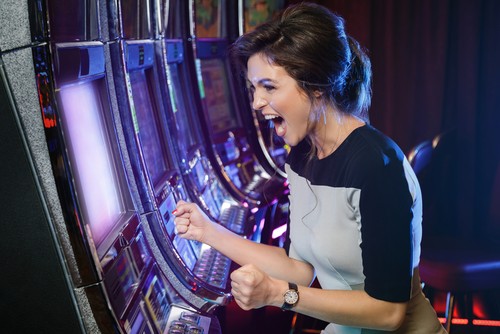 jeune femme heureuse qui joue aux machine à sous dans un casino