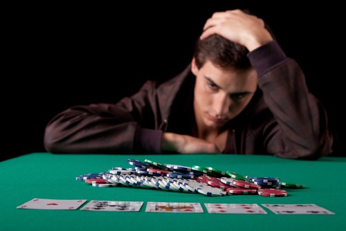 joueur de poker avec une multitude de jetons de casino ayant l'air abbatu