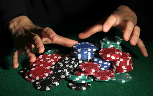 mains d'homme s'accaparant une pile de jetons de casino