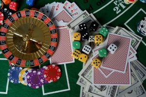 table de jeu avec une roulette, un jeu de cartes, des jetons, des dés et de l'argent liquide